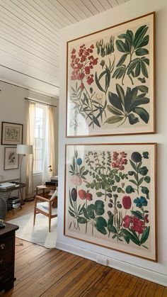 two paintings on the wall in a living room with wood floors and white walls, one is