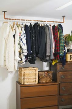 an organized closet with clothes hanging on the rails and baskets in front of it,