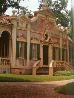 an old house with green shutters and a clock on the front door is shown