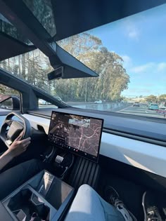 a person driving a car with a laptop on the dashboard and other vehicles in the background