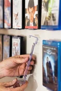 a person is holding a plastic object in front of some movies