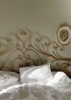 a bed with white sheets and gold headboard