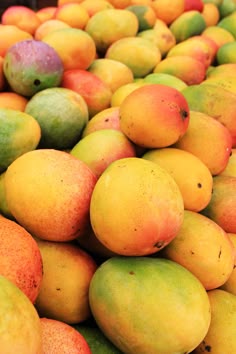 there are many mangoes and oranges on display