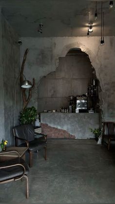 an empty room with two chairs and a counter in the corner, next to a potted plant