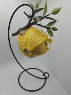 a piece of art that looks like a beehive hanging from a tree branch