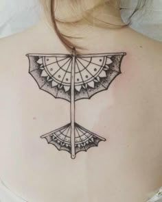 the back of a woman's shoulder with an umbrella tattoo