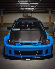 a blue car parked in a parking garage with its hood open and the hood up