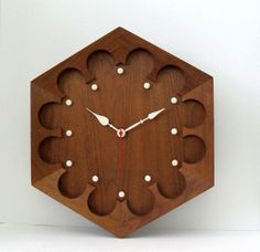 a wooden clock with holes in the middle on a white wall behind it is an image of a hexagonal object