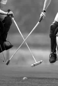 black and white photograph of two men playing golf on the field with their feet in the air