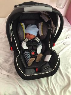 a baby in a car seat on top of a bed