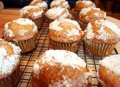 several muffins with powdered sugar on top sit on a cooling rack