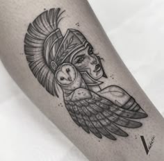 an owl tattoo on the leg of a woman's arm, which is wearing a headdress