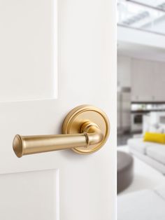 a door handle on a white door in a living room with couches and windows