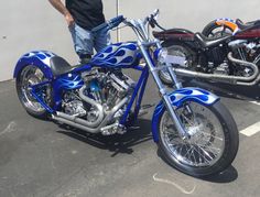 a blue and white motorcycle parked in a parking lot next to a man wearing jeans