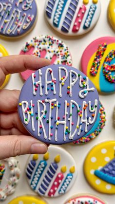 a hand holding a decorated birthday cookie with sprinkles