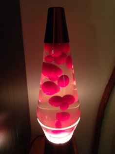 a lamp that is lit up with red rocks in the water on top of it