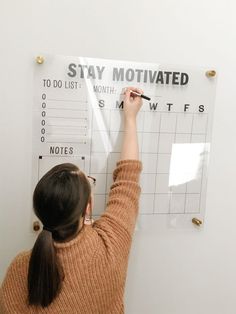 a woman writing on a wall calendar