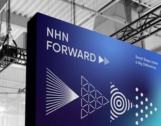 a large sign is hanging from the ceiling in an indoor area with metal beams and suspended overhead lighting