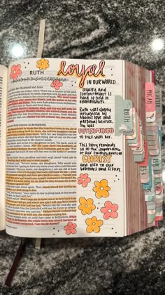 an open bible with flowers and words on the pages, sitting on a marble surface