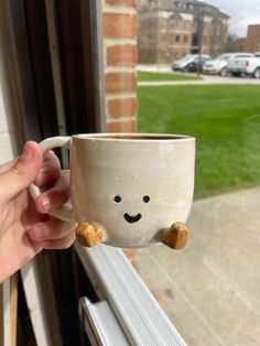 a hand holding a coffee cup with a smiley face on it and two nuts sticking out of the bottom