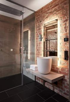 a modern bathroom with brick walls and black tile flooring, along with a white bowl sink