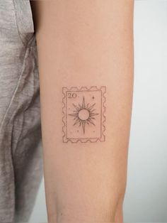 a woman's arm with a small sun tattoo on the back of her left arm
