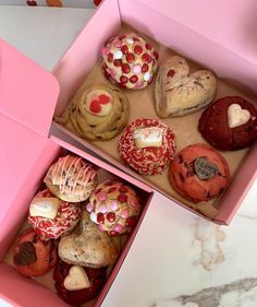 two pink boxes filled with different types of cookies