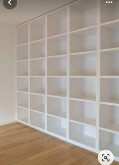 an empty room with white bookcases on the wall and wood flooring in front of it