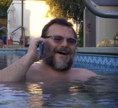 a man talking on a cell phone in a swimming pool