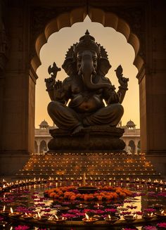 an elephant statue sitting in front of a fountain filled with water and lit up by candles