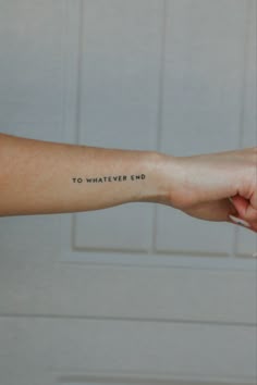 Woman shows off her small wrist tattoo that says “To Whatever End”