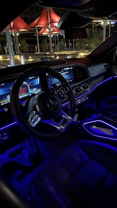 the interior of a modern car with blue lights and electronic controls on the steering wheel