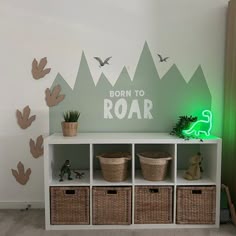 there is a shelf with baskets on it next to the wall that says born to roar