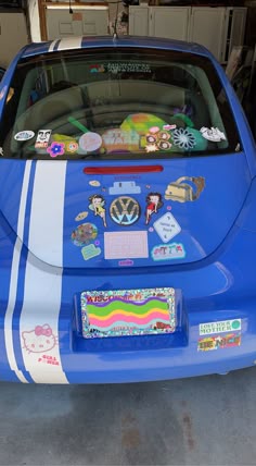 the back end of a blue car with stickers all over it's hood