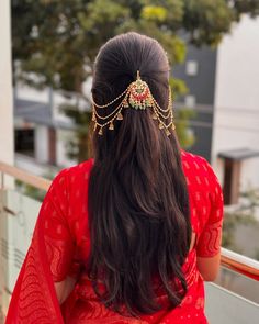 a woman with long hair wearing a red sari and gold head piece on top of her head