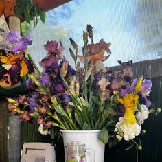 a vase filled with lots of purple and yellow flowers