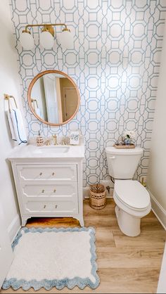 a bathroom with blue and white wallpaper, a toilet and sink in the corner