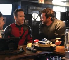 three men sitting at a bar talking to each other