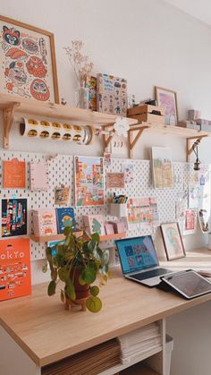 there is a desk with many pictures on the wall and a potted plant next to it