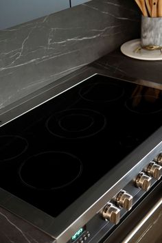 a stove top oven sitting in a kitchen next to a counter with utensils on it