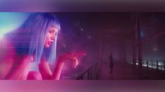 a woman with blue hair standing in front of a neon colored background and looking at her cell phone