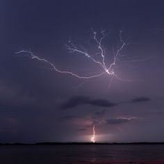 a lightning bolt is seen in the sky over water