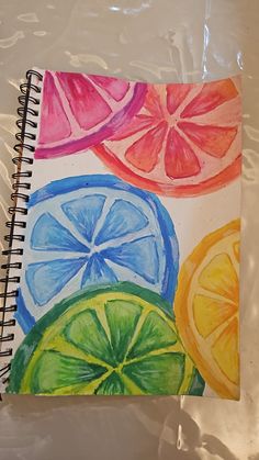 a spiral notebook with watercolor drawings of lemons, oranges and grapefruit
