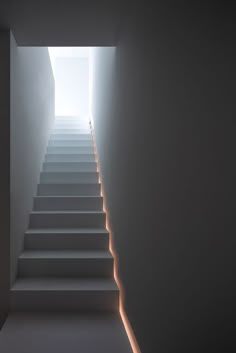 the stairs are illuminated by light coming from behind them in this minimalist white room