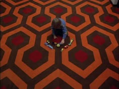 a young boy sitting on the floor with his skateboard in front of an orange carpet