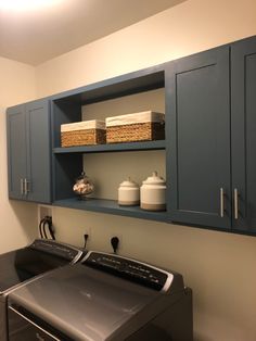 a washer and dryer in a laundry room with blue cabinetry on the wall