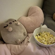 a bowl of popcorn and a stuffed animal are on the bed next to each other
