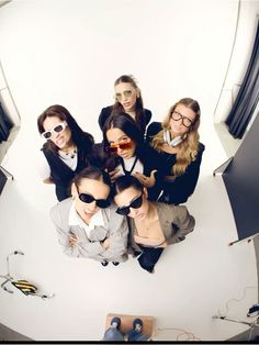 a group of people standing around each other in front of a white wall with sunglasses on