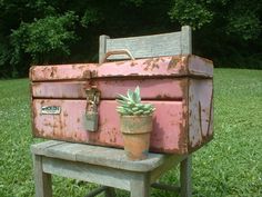 an old suitcase sitting on top of a wooden bench next to a potted plant