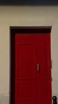 a red door is open in front of a white wall with a black cat sitting on it
